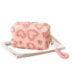 Pink plush cosmetic bag with fluffy heart pattern and wristlet for travel storage