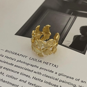 Nahaufnahme eines goldenen Ginkgoblatt-Rings auf einer kunstvollen Magazinseite
