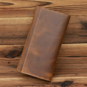 Detail of vintage brown crazy horse leather wallet with stitching on wood background
