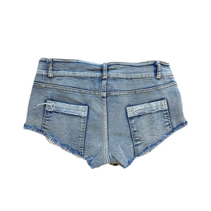 Dettaglio degli shorts in denim azzurro con orli sfilacciati e doppie tasche posteriori