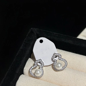 Detail of silver gourd earrings with zircon pave and pearls in a beige jewelry box