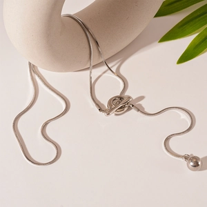 Close-up of minimalist silver snake chain necklace with toggle clasp and metal ball pendant