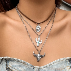 Detail of layered bohemian necklace featuring turquoise cactus and retro bull skull pendants