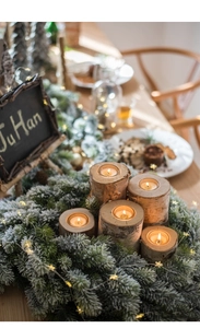 Close-up of set of 5 natural birch wood candle holders with rustic bark texture on table