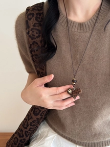 Close-up of heart-shaped leopard print pendant necklace on a brown sweater