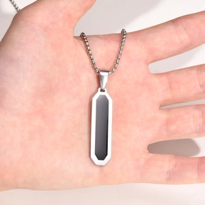 Detailed view of a geometric rectangular pendant with black inlay on a stainless steel chain