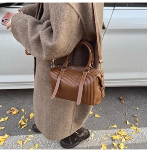 Detail der dunkelbraunen Falten-Handtasche getragen von einem Modell im Wollmantel