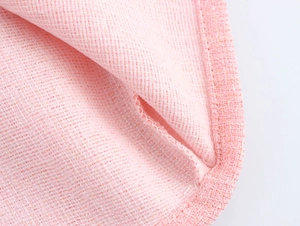 Detailed close-up of pink tweed fabric texture and pocket design on a mini dress