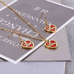 Détail d'un ensemble collier et boucles d'oreilles dorés avec pendentifs cœur rouges