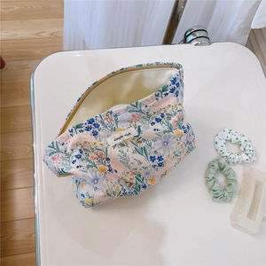 Detailed view of floral cotton makeup bag with Simple Wish label and zipper on white surface