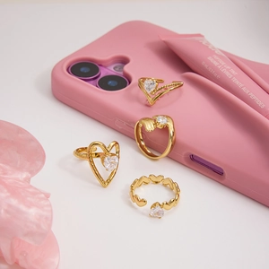 Detailed view of a four-piece gold ring set with zirconia hearts on a clean white desk