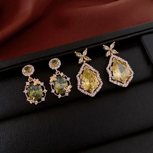 Détails de boucles d'oreilles fleur et papillon dorées avec pierres vertes et jaunes