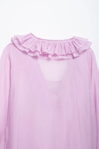 Detail view of pink layered ruffle collar and V-neckline on soft woven fabric shirt