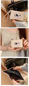Detail of beige dachshund embroidered wallet with wrist strap and internal slots