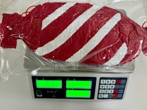 Detailansicht des 160g leichten rot-weiß gestreiften Zuckerstangen-Plüschkissens auf Waage