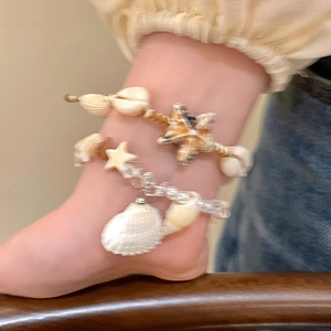 Detail view of beach style bracelet with natural conch, starfish, and pearls on wrist