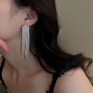 Gros plan de boucles d'oreilles à pompons longs et cristaux portées par un mannequin