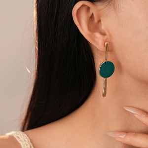 Boucles d'oreilles émaillées vertes asymétriques en or portées par le mannequin