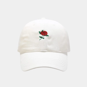 Detailed close-up of intricate red rose embroidery on a classic white cotton baseball cap