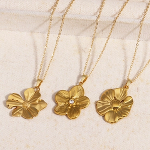 Nahaufnahme von drei goldenen Blumenanhängern mit feinen Ketten auf Leinenhintergrund
