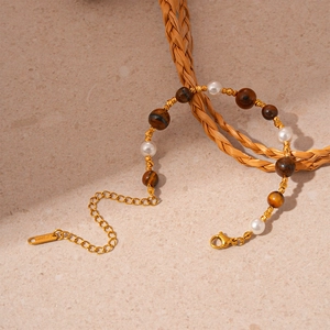 Détail d'un bracelet vintage en œil de tigre et perles avec étiquette gravée S.STEEL