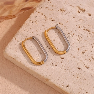 Close-up of oval stainless steel hoop earrings in mixed gold and silver tones
