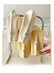 Détail de chaussettes mi-mollet en coton côtelé crème et jaune avec étiquettes cousues