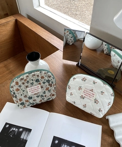 Detail of quilted floral and cherry cosmetic bags with green piping and zip closure