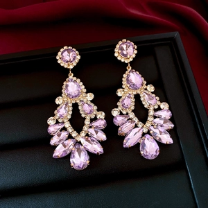 Macro view of purple teardrop crystal tassel earrings on premium red silk background