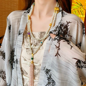 Close-up of double-layer pearl necklace with floral charms and pink fringe tassel
