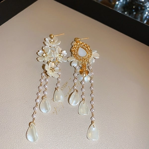 Detail of asymmetrical floral pearl tassel earrings with gold-toned metal accents