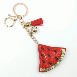 Detail of watermelon slice keychain with red rhinestones, gold clasp and red tassel fringe