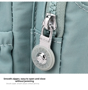 Detail of smooth zipper with circular gray rubber puller on light green nylon bag