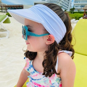 Close-up of a white pleated open-top sun hat and glittery blue sunglasses for kids on sand