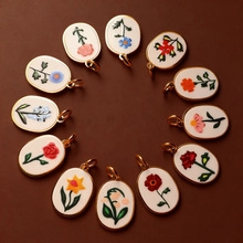 Macro view of twelve oval floral charms with golden edges and diverse botanical patterns