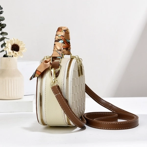 Close-up of cream round mini bag with checkered texture and silk scarf handle detail