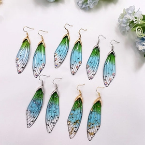 Macro shot of S925 silver cicada wing earrings with green blue gradient and rhinestones