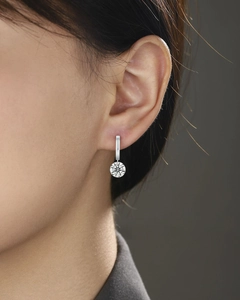Macro detail of silver dangle earring featuring a brilliant round-cut moissanite stone