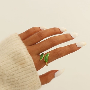 Detail of gold-plated leaf ring with green enamel finish on a model's finger
