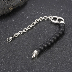 Detailed macro of silver chain bracelet featuring matte black beads and pig nose buckle