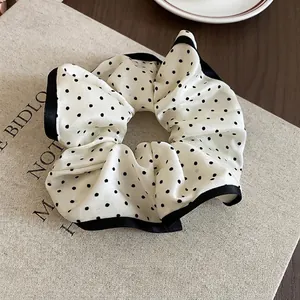 French vintage polka dot scrunchie with black satin edges on a decorative book