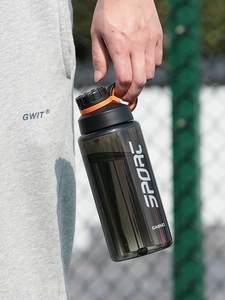 Detail of a large dark grey sports water bottle with a secure black and orange lid