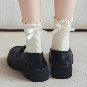 Close-up of cream mid-calf socks with ruffle trim and satin bow on the heel back