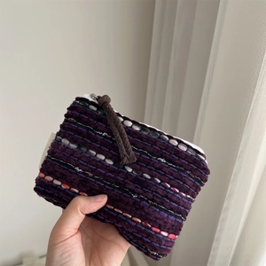 Close-up of a hand holding a retro woven striped mini coin purse with a rope zipper pull