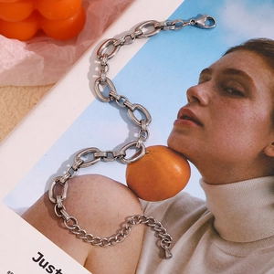 Detail of silver textured chunky link bracelet with lobster clasp on a fashion magazine