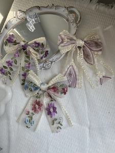 Detailed view of three elegant lace embroidery bow hair clips with purple floral patterns