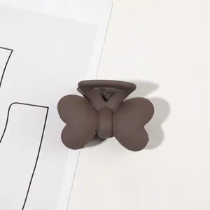 Detail view of a matte brown butterfly hair claw clip featuring rounded wings and teeth
