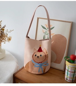 Detailed shot of canvas bucket bag featuring a cute orange cat illustration and plaid strap