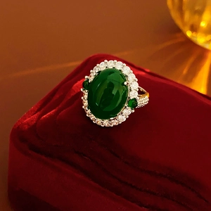 Macro shot of oval green zircon ring with halo diamond setting on red velvet box