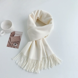 Detailed texture of white cashmere-like scarf featuring soft tassels and minimalist style